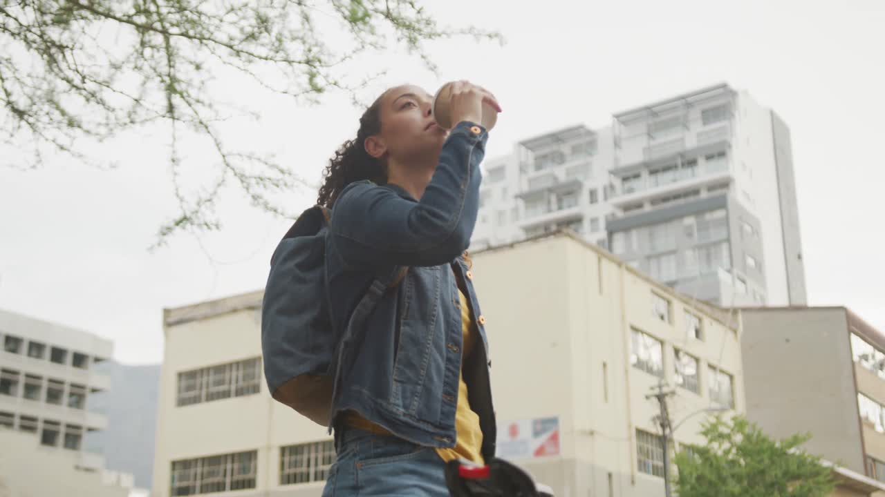 Donna birazziale felice in città, con uno zaino e che beve caffè da asporto