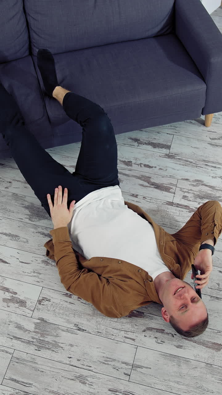 Man relaxing at home on floor. Young man relaxing on the floor and talking on mobile phone
