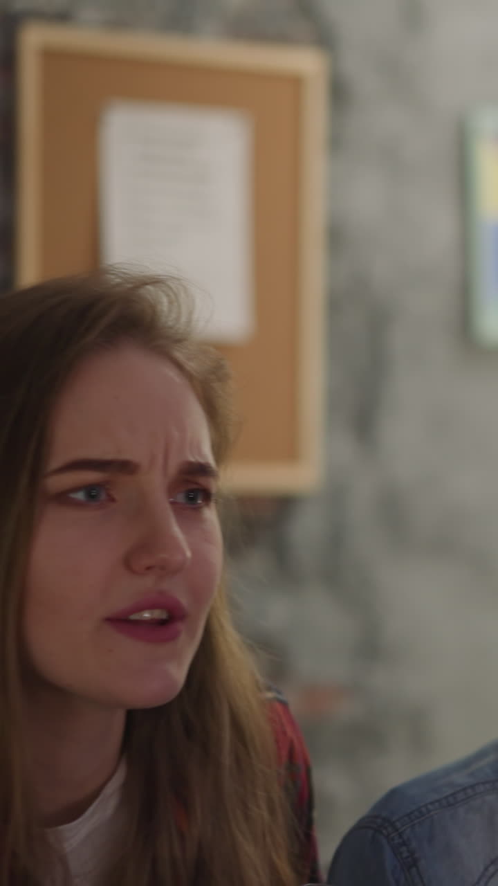 Nervous young people watch complicated football match via TV sitting in living room slow motion. Sports fans follow favorite team performance in evening