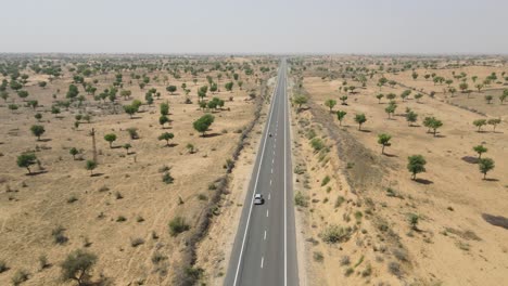 aerial drone shot of a vehicle cutting across long, winding roads through the barren desert terrain.