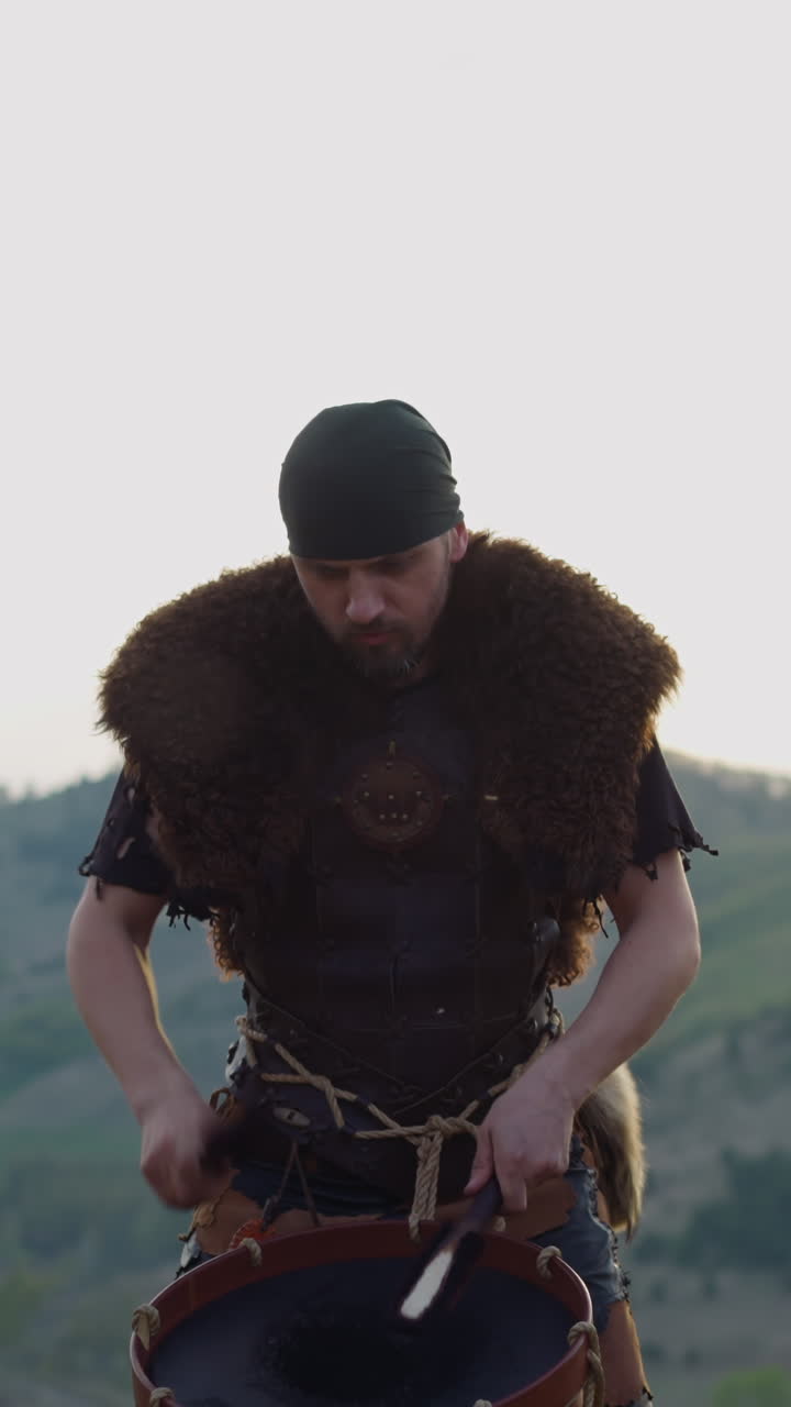 Concentrated musicians in ethnic clothes play drums in green mountain valley slow motion. Altai culture representation. Folk music festival