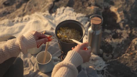 from above view of anonymous woman cooking fresh noodles on portable stove at campsite in england, uk
