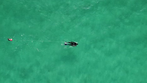 Solo-spearfisher-in-vast-turquoise-sea,-trailing-a-safety-buoy-during-a-clear-day-in-Sardinia's-waters