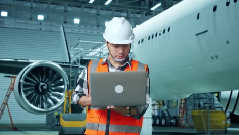 mecánico de aviones trabajando en una computadora portátil en el hangar