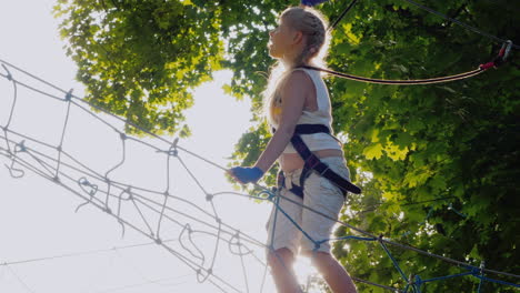 a brave child walks along a tightrope between tall trees active childhood and fun