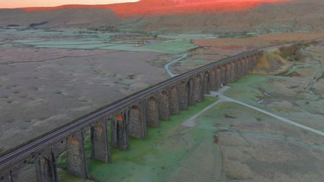 colina de páramo iluminada por la luz del amanecer de invierno y arcos de viaducto atrapando la luz