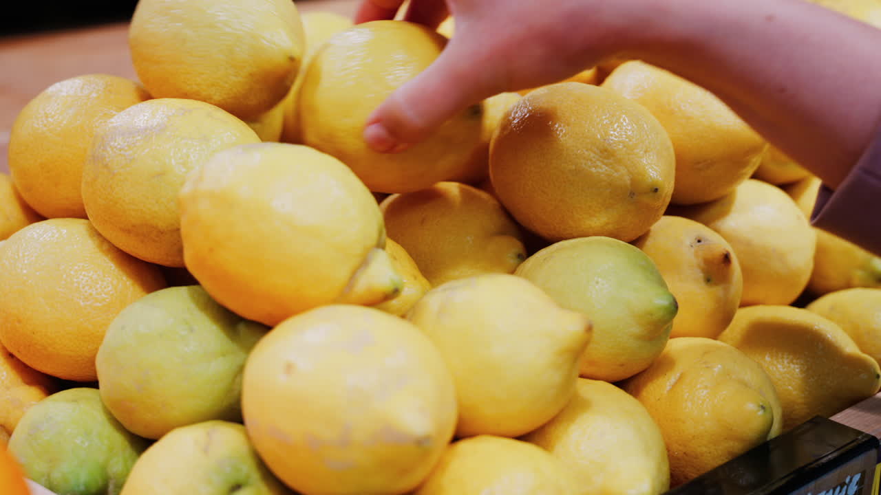 Close up of a woman's hand picking up lemons at a market