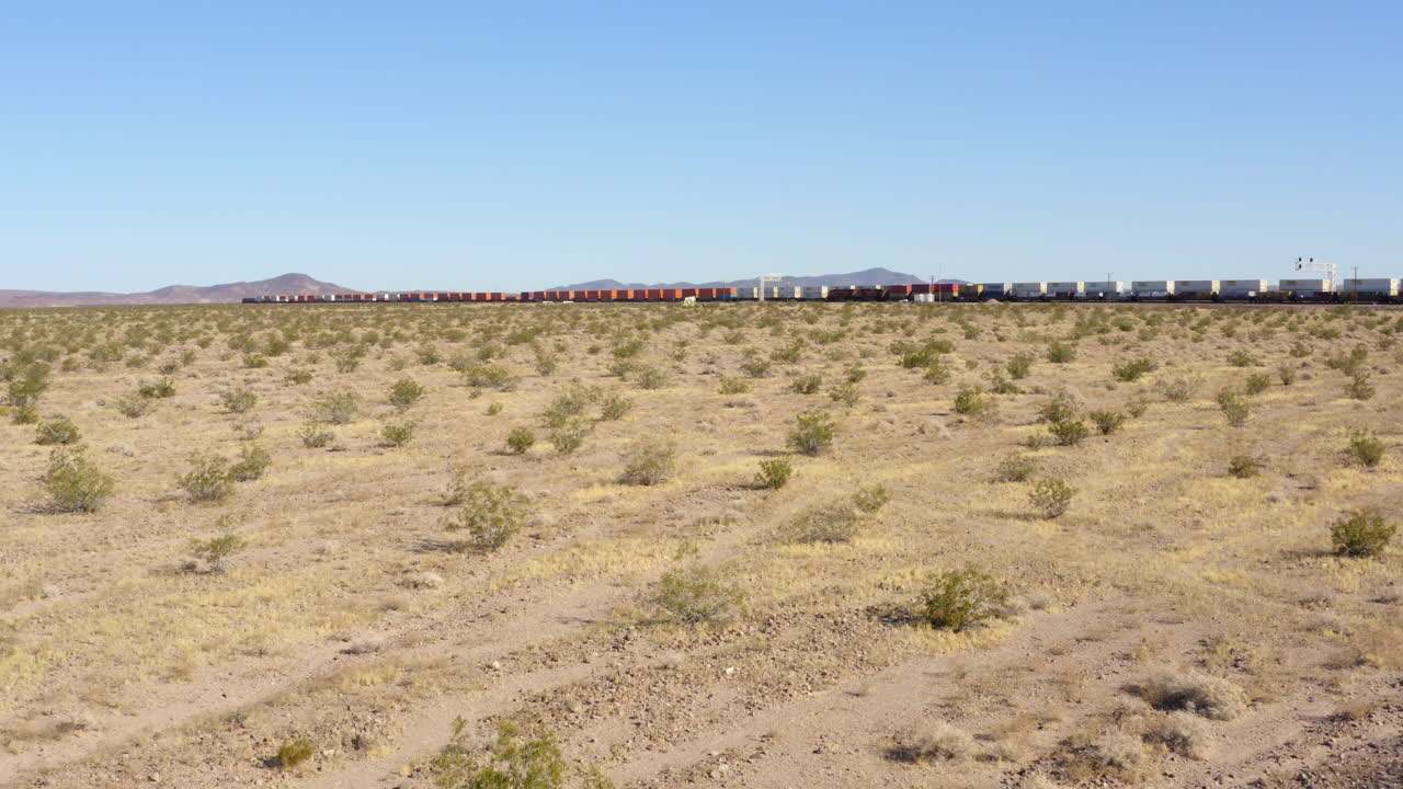 vista baja de dos trenes de carga extremadamente largos que se pasan entre sí en vías de tren rectas en el desierto