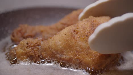 close up shot of crispy fried chicken legs in a frying pan.