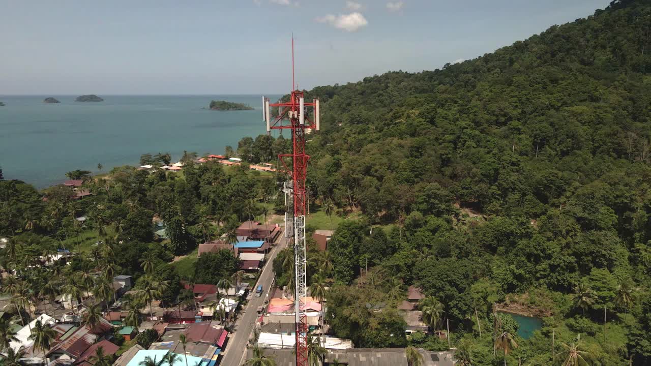 vista aérea de pájaros teledirigidos de una torre de telecomunicaciones de 4g y 5g en un pequeño pueblo costero en una isla tropical en el sudeste asiático con el océano y las islas en el fondo