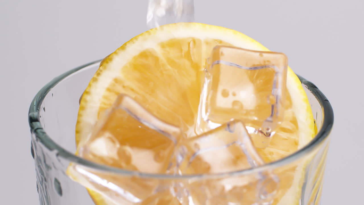 얼음과 레몬 조각이 있는 유리에 쏟아지는 차가운 신선한 탄산수-1