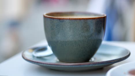 primer plano de una taza de café de cerámica de color oscuro en un platillo