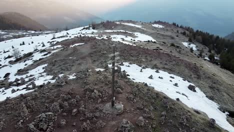 Aerial-orbit-shot-of-summit-cross-on-mountaintop-of-Alps-during-sunny-day-with-snow-during-hike-in-Austria