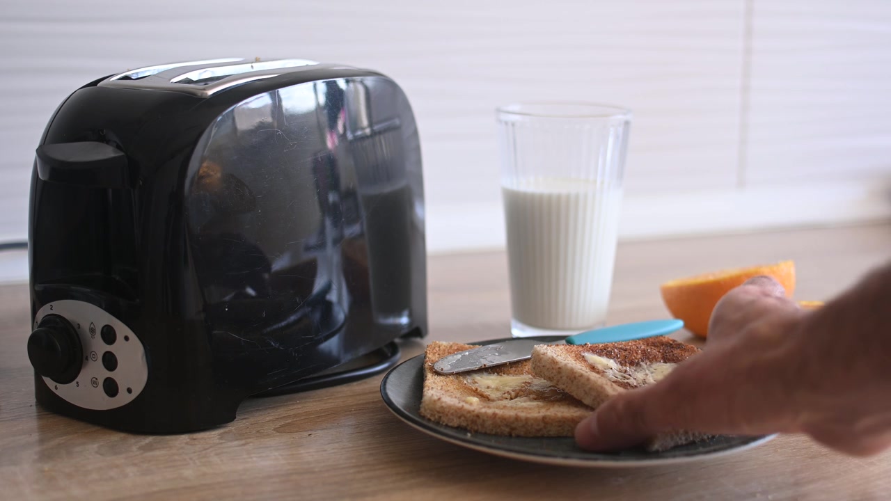 Hand picking up buttered toast from a breakfast plate