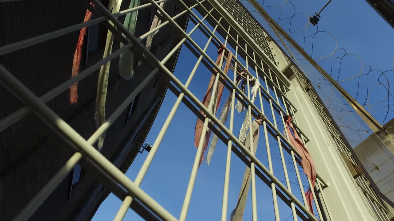 valla metálica de la prisión con pulseras de prisioneros que contienen mensajes de libertad.