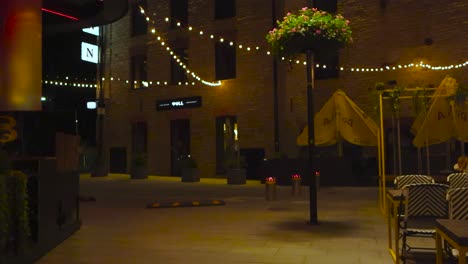 Street in where people are eating and drinking during night or evening called Rotermanni block or street. Dining tables, chairs and cozy lamps and lights are illuminating surroundings like limestone.