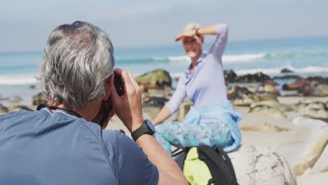 Senior-hiker-man-taking-pictures-of-senior-hiker-woman-using-digital-camera-on-the-beach.