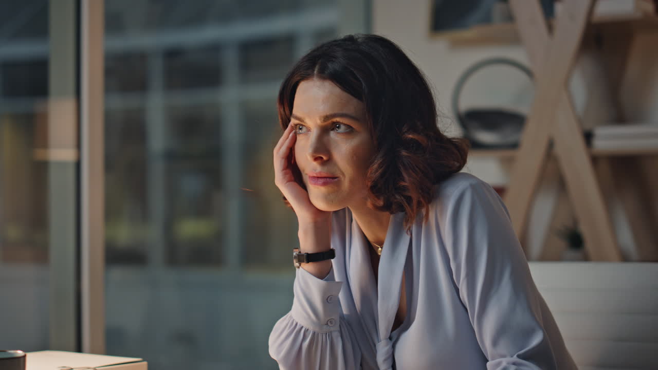 Late worker pondering project sitting evening workplace closeup. Tired woman