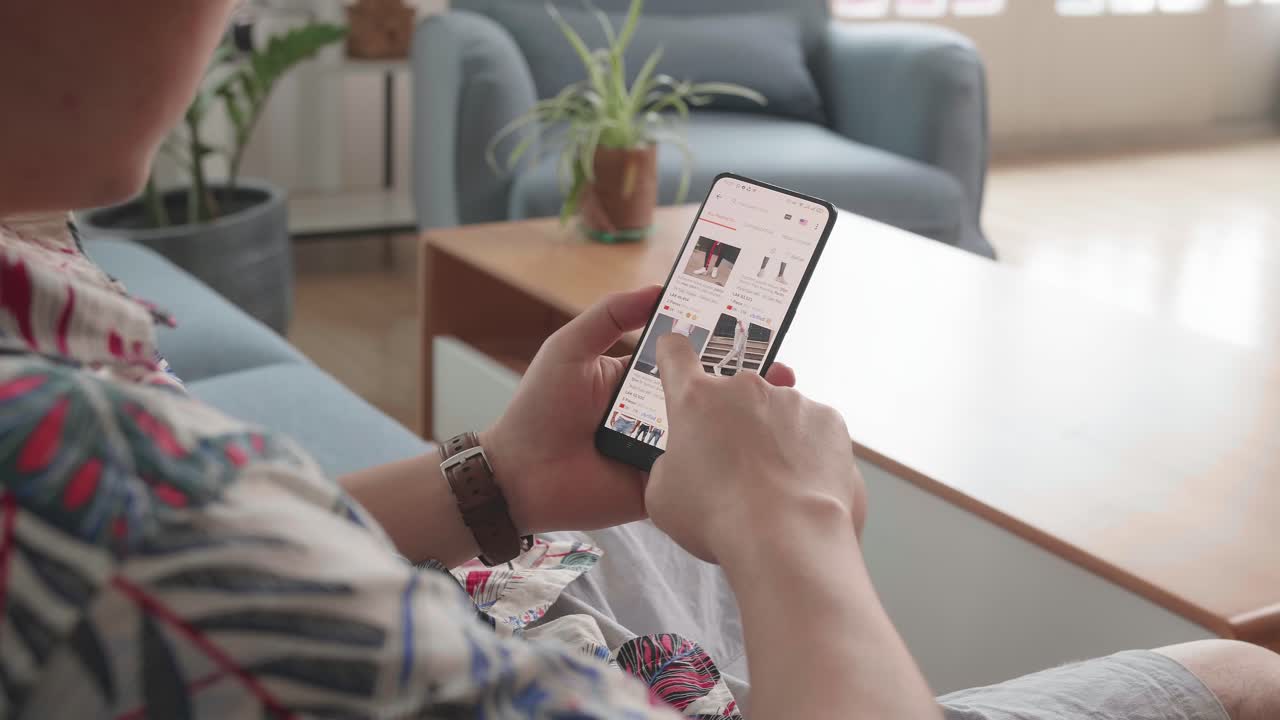 Man Looks At Goods In Online Store Clothing. Buy Fashion Clothes Directly On Smartphone