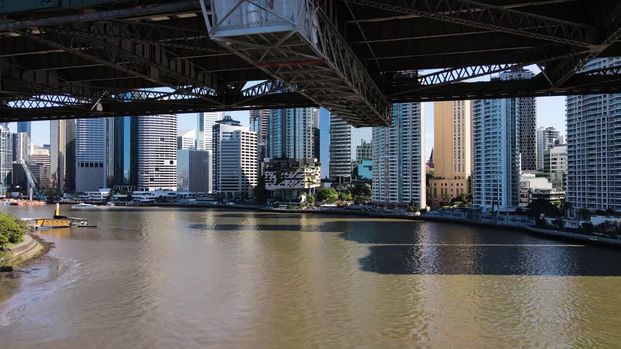 Revealing pass under the iconic Story Bridge with panoramic views of the towering Brisbane City skyline and surrounding area. Aerial view