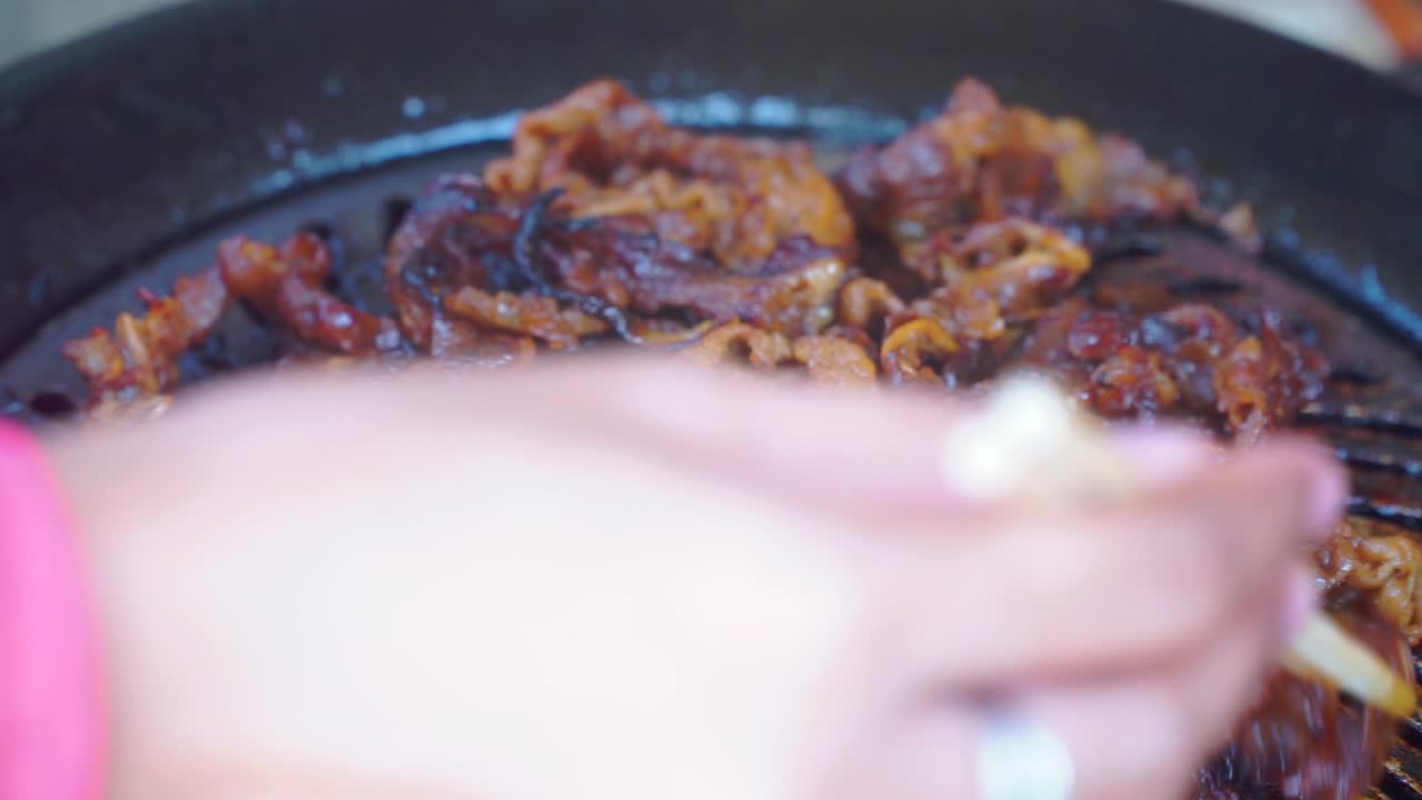 Close up shot hand of people cooking Barbeque&nbsp;meat using chopsticks on the grill pan
