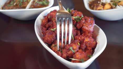 Fork-picks-up-gobi-manchurian,-a-bite-of-fried-cauliflower-in-spices,-slider-close-up-4K