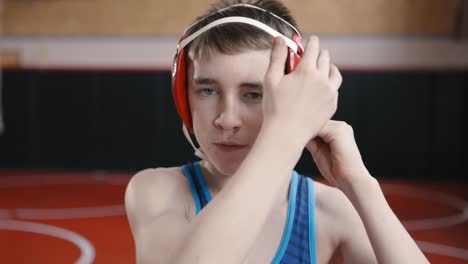 teenage wrestler putting on his headgear