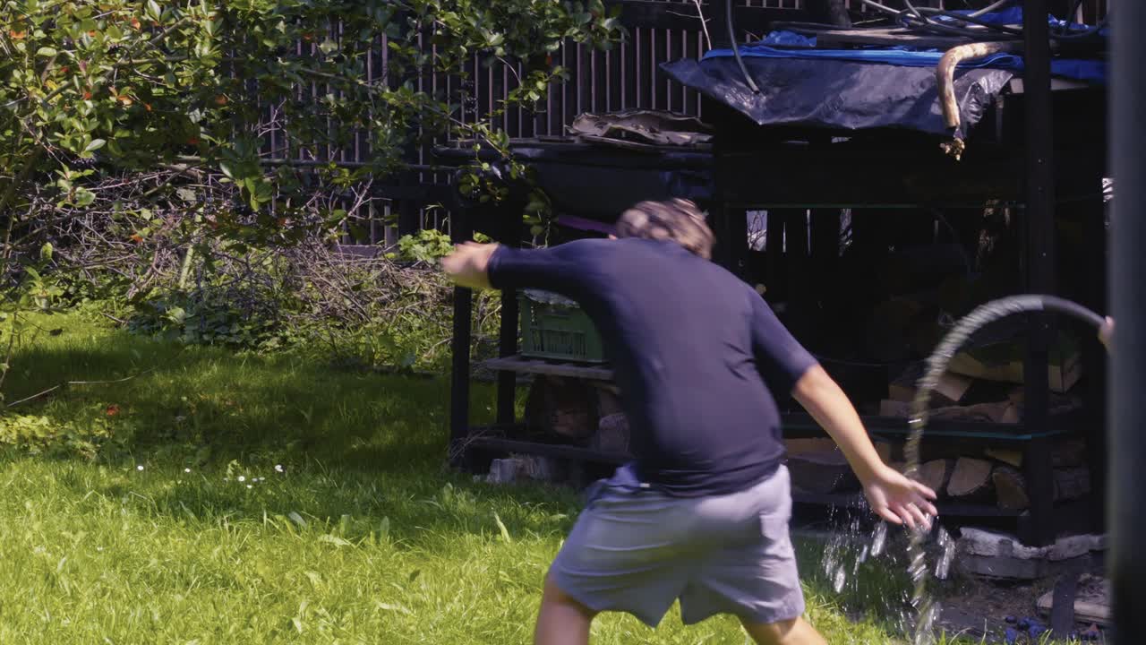 Laughing children enjoy water fight fun with garden hose in summer