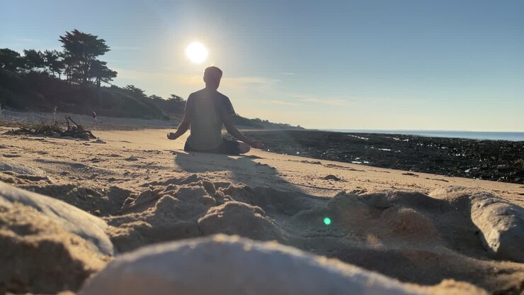 Uomo medita su una spiaggia tranquilla al tramonto.