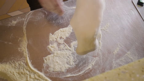 top view of a chef kneading pizza dough on a restaurant kitchen countertop