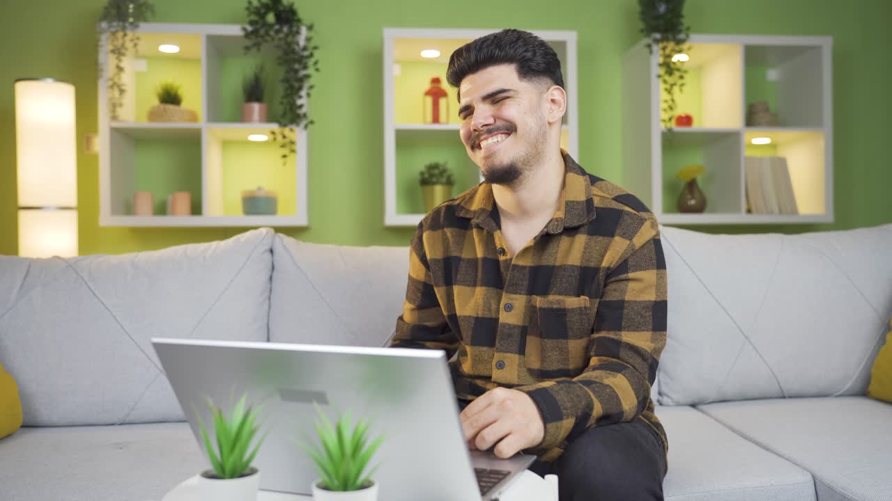 un joven riéndose de lo que ve en la computadora portátil.