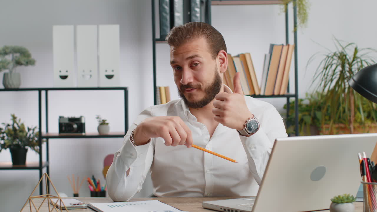 Happy business man looking approvingly at camera showing thumbs up like positive sign good news