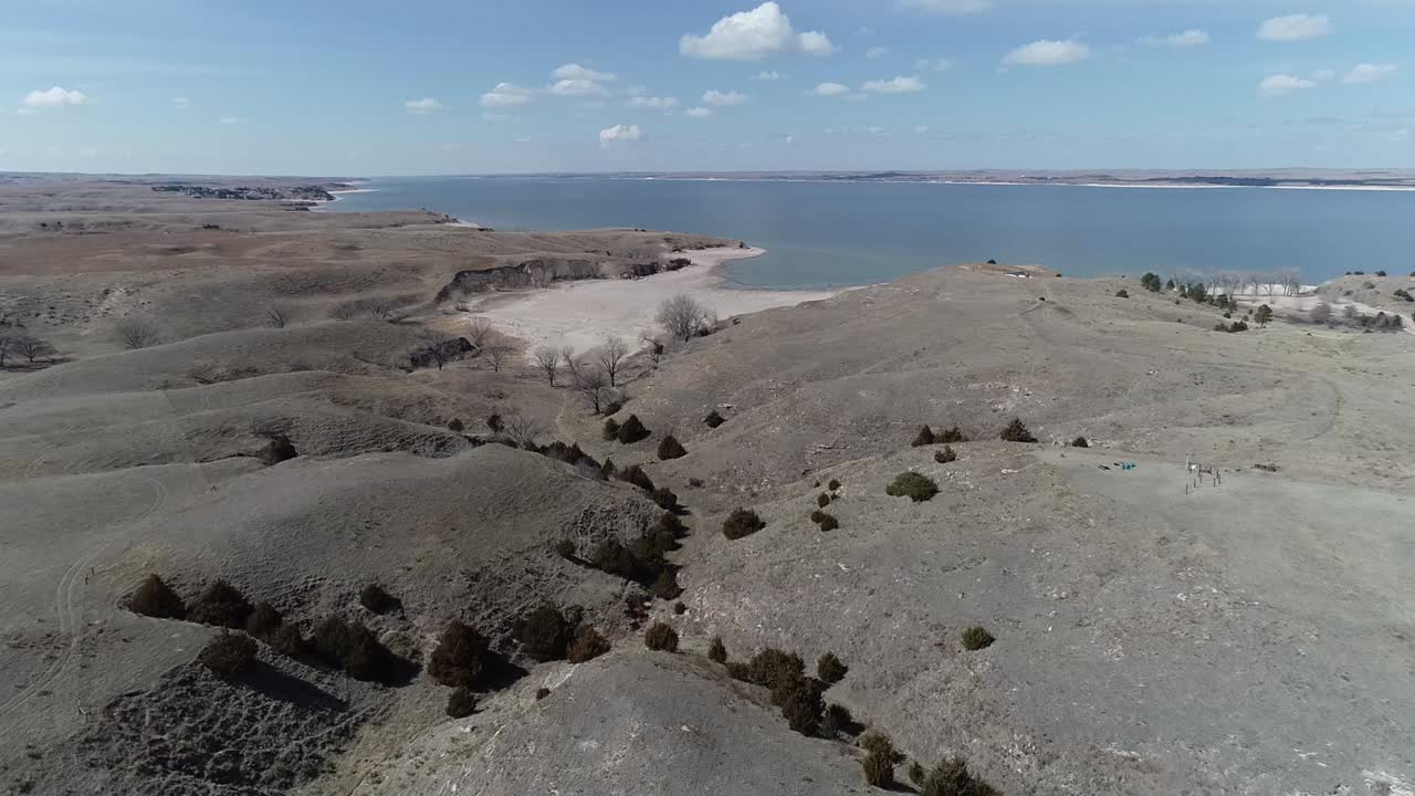Flyver mod en sø forbi et landsted, der ligger på toppen af en bakke
