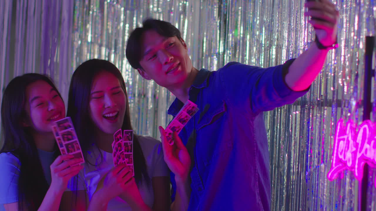 grupo de amigos tomando selfies divirtiéndose mirando las impresiones de la cabina de fotos en un club nocturno o feria 3