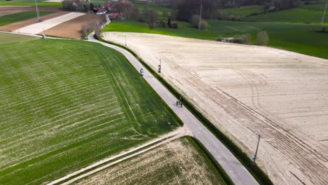 Aerial-tilt-up-with-cyclist-enjoying-their-biking-vacation-between-Belgian-agricultural-fields-on-a-cloudy-day