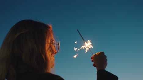 mujer sosteniendo bengalas en la playa al atardecer disfrutando de la celebración de nochevieja ondeando juguetonamente fuegos artificiales de bengala niña celebrando el día de la independencia el 4 de julio