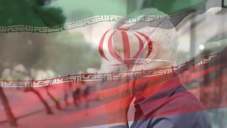 Animation-of-flag-of-iran-waving-over-man-wearing-face-mask-during-covid-19-pandemic