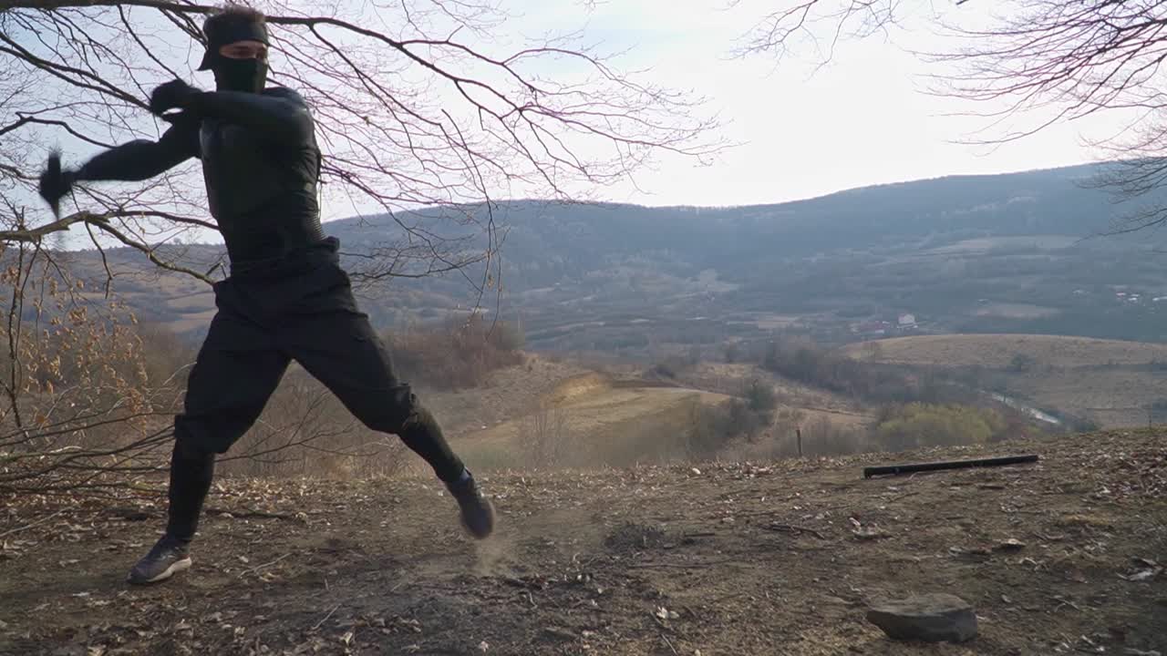 A stealth ninja in sleek black gear stands poised in an outdoor setting, brandishing his finely crafted sword in a dynamic combat stance. Ideal for martial arts and action-themed projects.