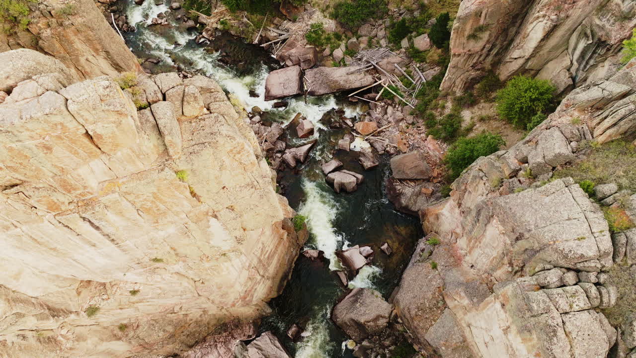 drone shot looking down at geologic rock formations in canyon with river running