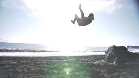 joven viajero haciendo una voltereta hacia atrás en cámara lenta en la playa negra en islandia