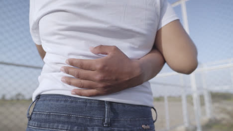close-up of a man's hand on a woman's waist during a hug while they are in the garden of their house.