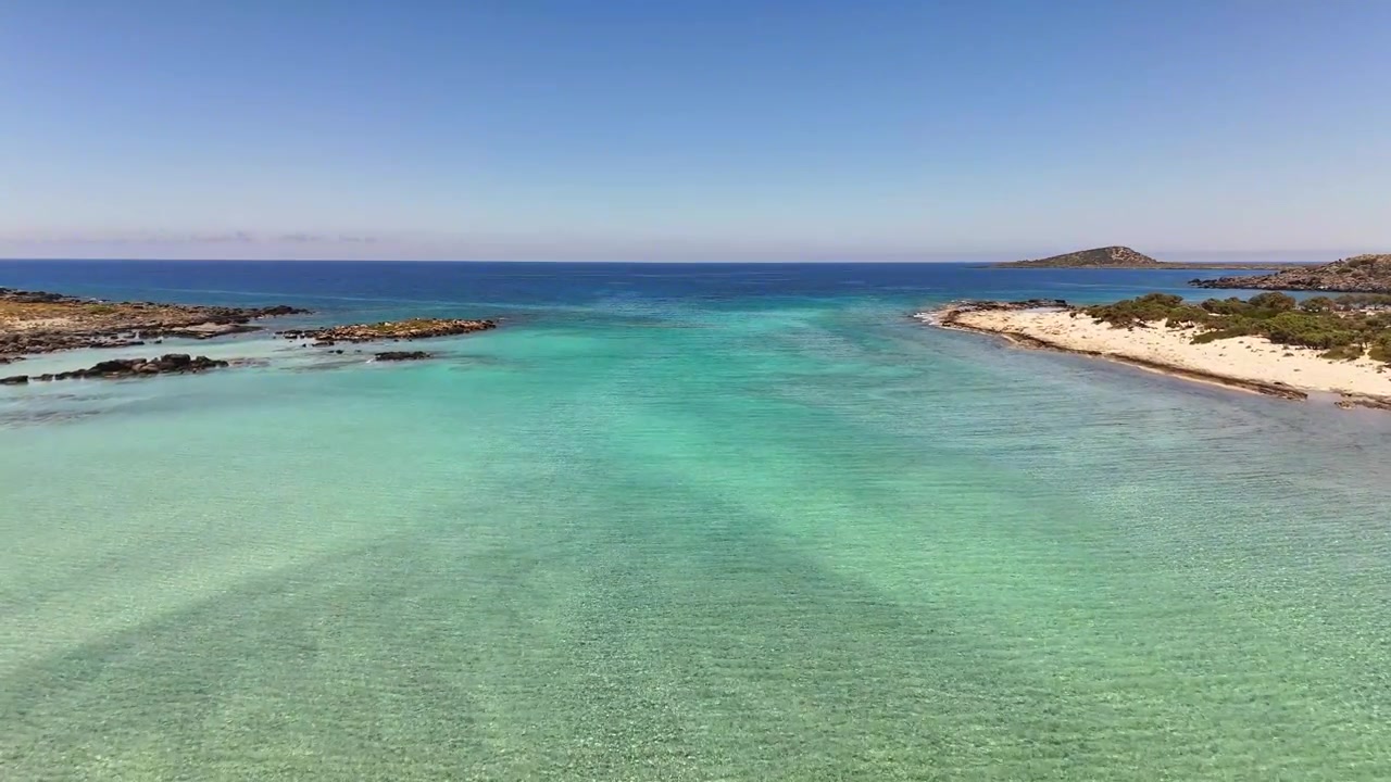 Acqua turchese e poco profonda della laguna si estende tra le rive sabbiose presso la spiaggia di Elafonissi, Kissamos, Chania, Creta, Grecia, durante un sorvolo in avanti con drone