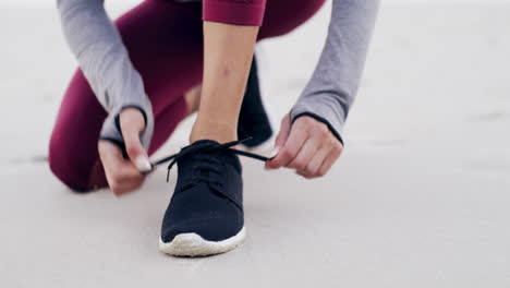 mujer atando sus zapatillas de correr en la playa