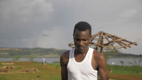 Nahaufnahme-Eines-Gesichtes-Eines-Jungen-Afrikanischen-Mannes,-Der-An-Einem-Strand-Am-Ufer-Des-Viktoriasees-Tritte-Macht