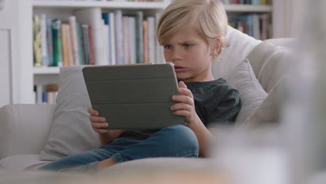 happy little boy using digital tablet computer playing game relaxing on sofa at home child browsing online with mobile device technology anti social addiction concept 4k