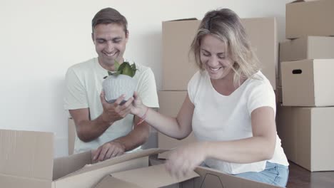 happy couple unpacking things in new apartment