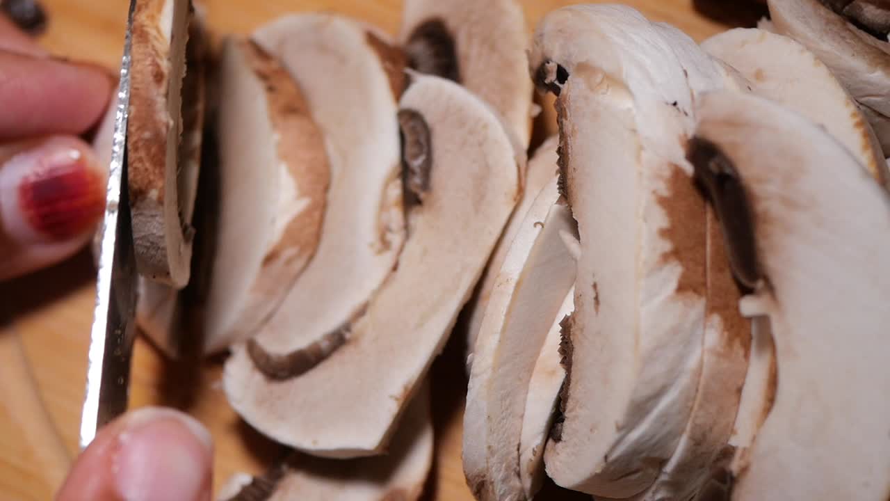 Close-up of hand slicing fresh mushrooms on a cutting board
