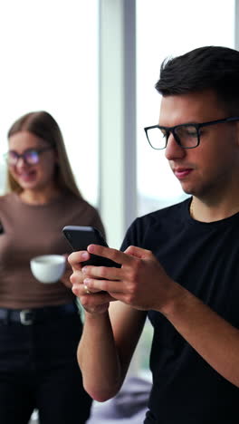 using modern gadgets during lunch break in office. phone addicted people concept. panoramic windows at backdrop in blur. vertical video