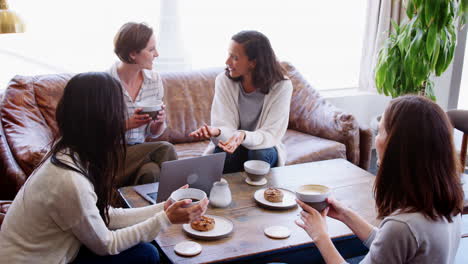 cuatro mujeres jóvenes adultas charlando sobre café y pastel en una cafetería