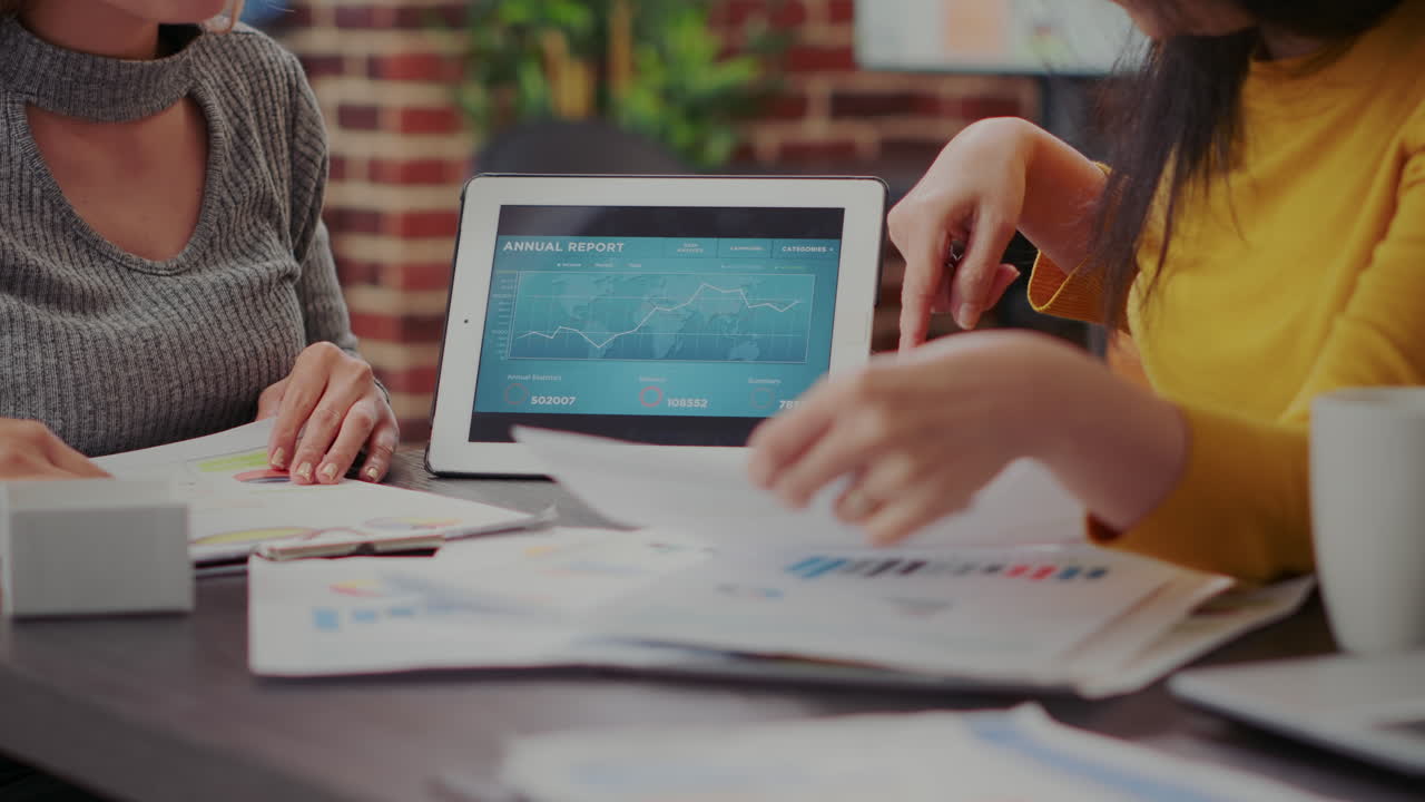 Women analyzing financial report on digital tablet